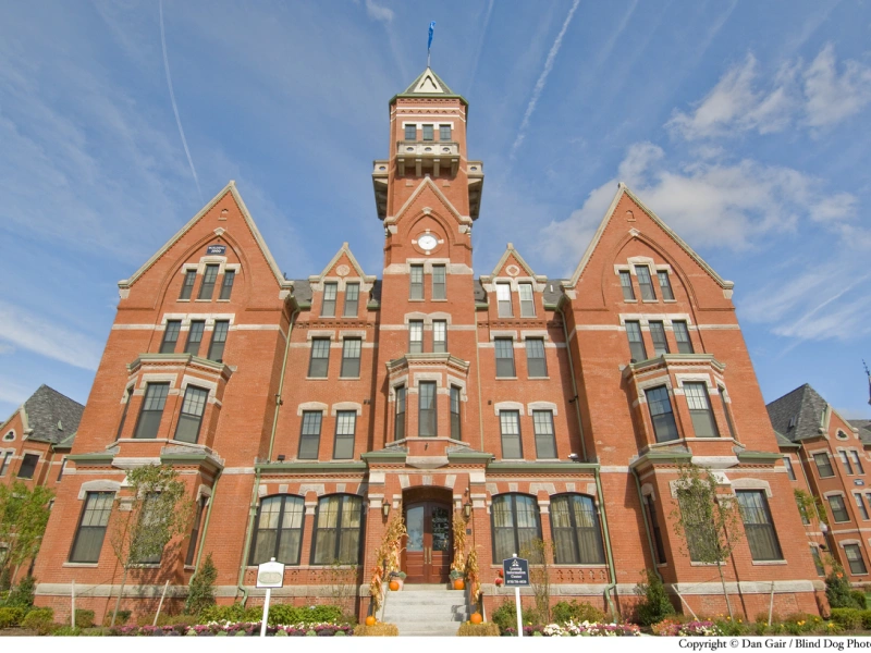 Historic red brick building with tall central tower repurposed as upscale Avalon Danvers apartments