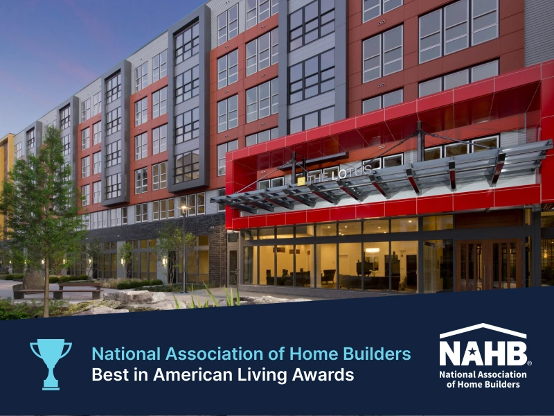 Modern apartment building with bold red entrance canopy in Best Mixed-Use Community by NAHB Award graphic