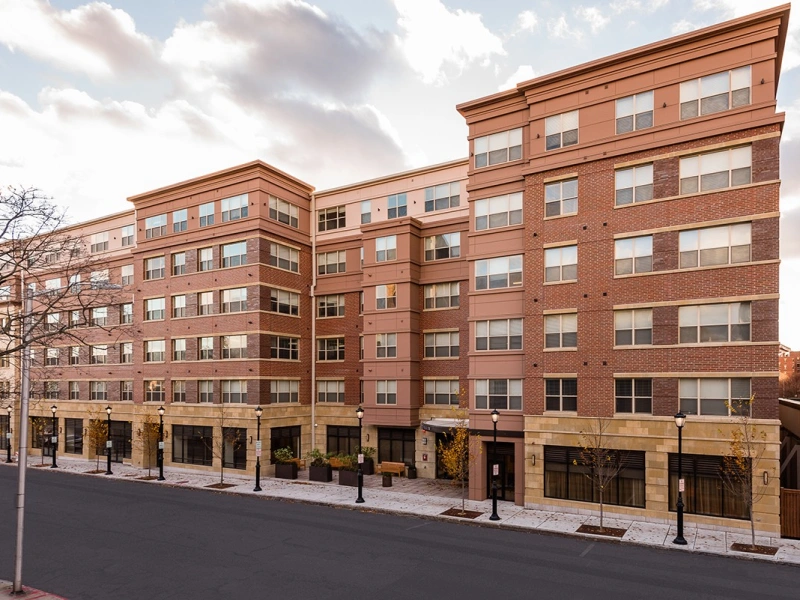 Mid-rise brick Halstead Malden apartment building with large windows on a quiet city street