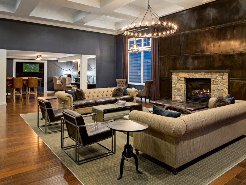 Elegant clubhouse lounge with leather armchairs, tufted sofas, and cozy fireplace in Halstead Tewksbury, MA