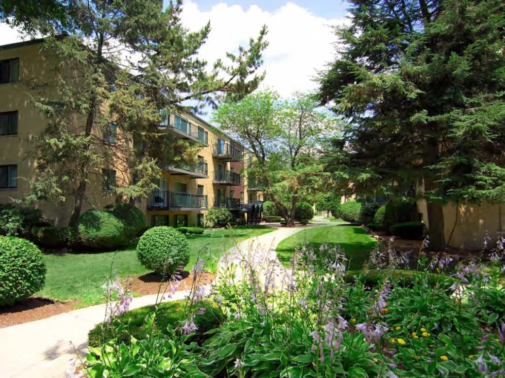 Peaceful landscaped path winding between residential buildings and manicured shrubs