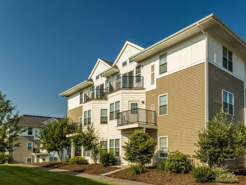 Contemporary three-story apartment building with balconies and white siding against blue sky