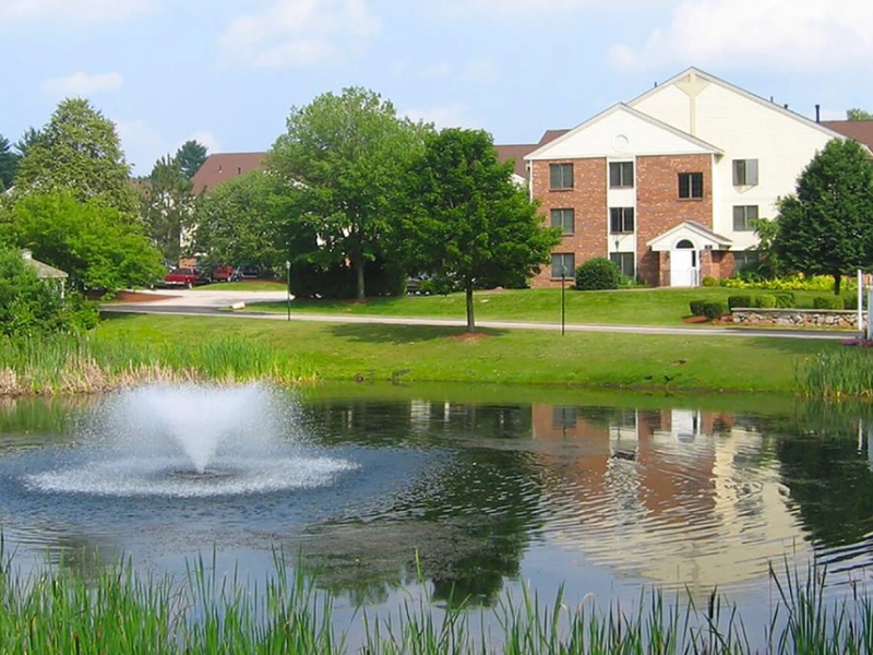 Residential property with scenic pond and fountain surrounded by greenery in Manchester, NH