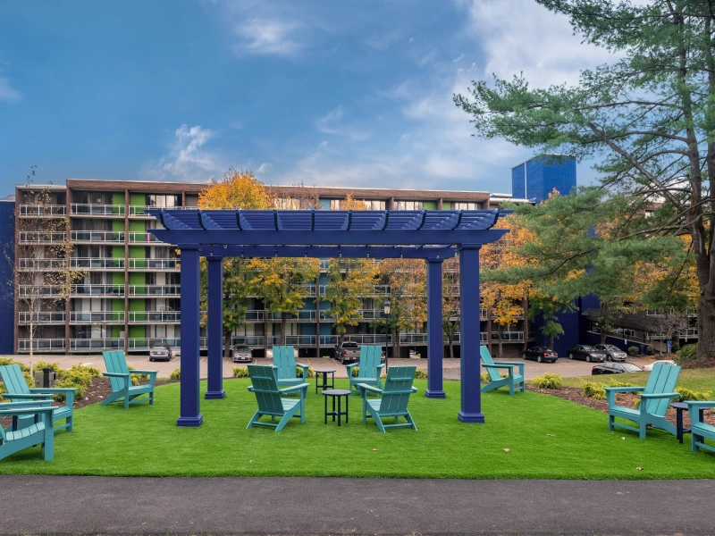 Modern apartment complex in Framingham with bold blue pergola and colorful outdoor seating