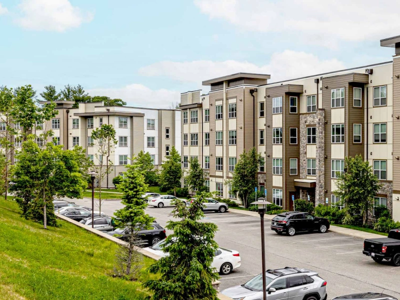 Four-story multifamily residential development with large windows and outdoor surface parking