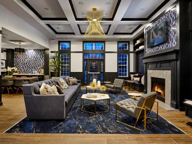Sophisticated resident clubhouse featuring geometric lighting, navy carpet, and a wall-mounted TV