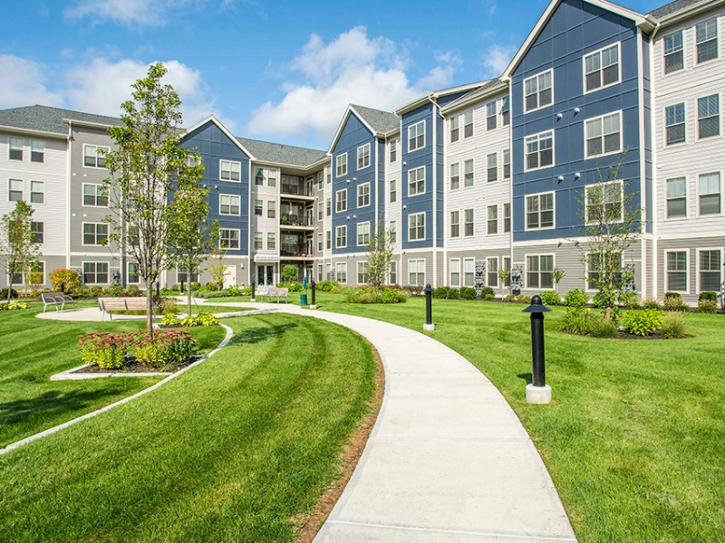 Bright apartment buildings with blue and white siding, bordered by clean landscaping and walkways