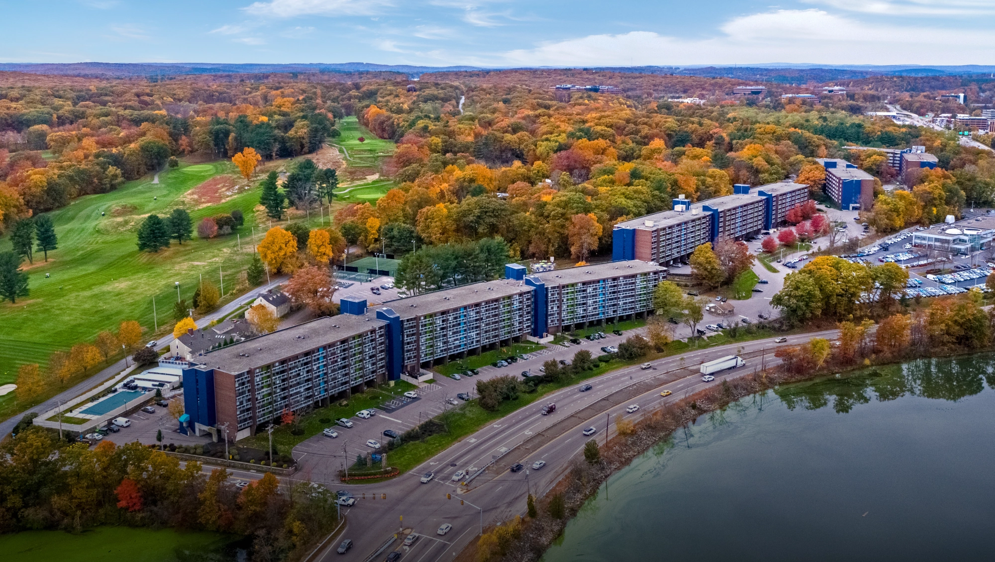 Aerial view of Halstead Framingham apartments surrounded by forest and golf course in autumn
