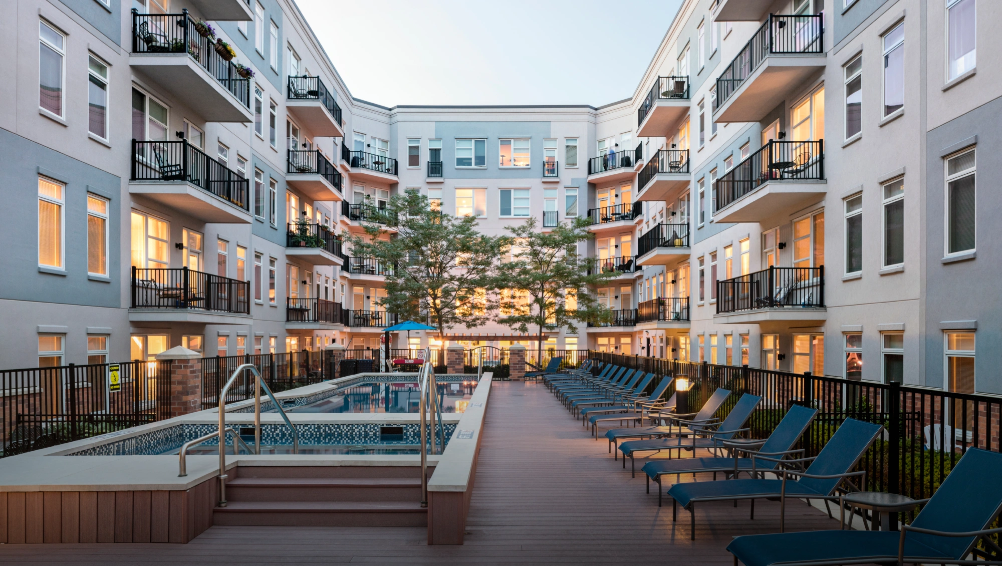 Halstead Hoboken apartment complex courtyard featuring swimming pool, trees, and patio seating area