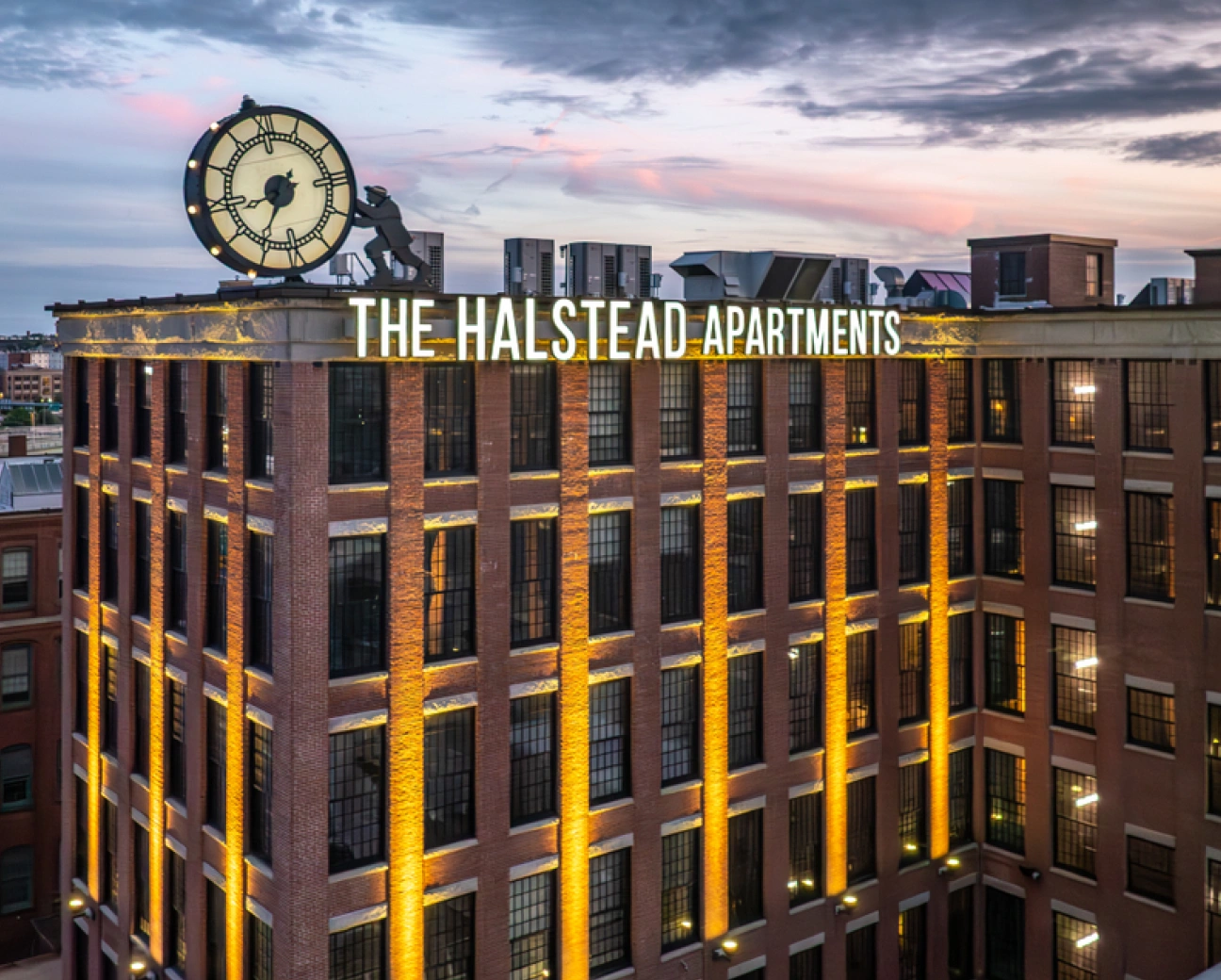 The Halstead Apartments building in Providence with rooftop clock and dramatic sunset lighting across brick facade