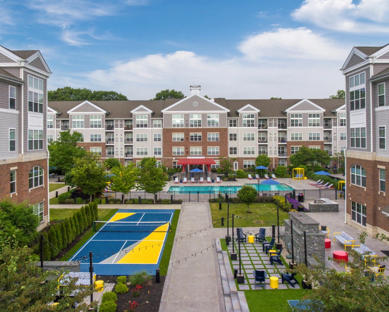 Aerial view of an apartment courtyard with recreational facilities surrounded by landscaped greenery and modern units