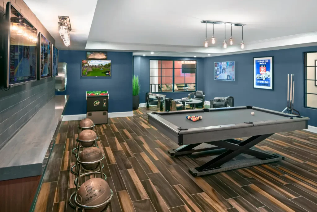 Stylish game room with pool table, arcade machine, bar stools, and multiple mounted TVs in Halstead Danvers