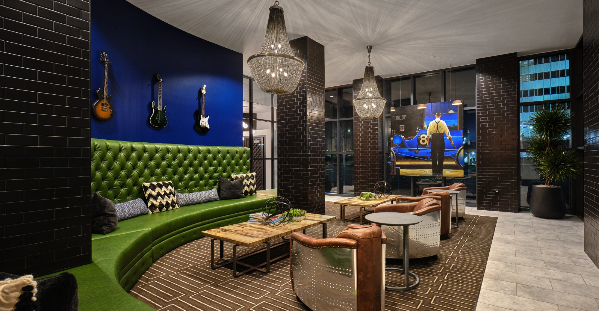 Stylish apartment lounge with green tufted couch and guitars on blue wall in Halstead Station