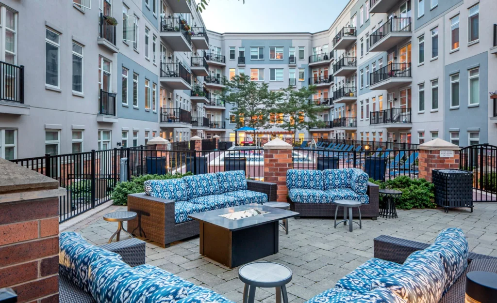 Outdoor courtyard with cushioned seating area and fire pit surrounded by luxury apartment balconies