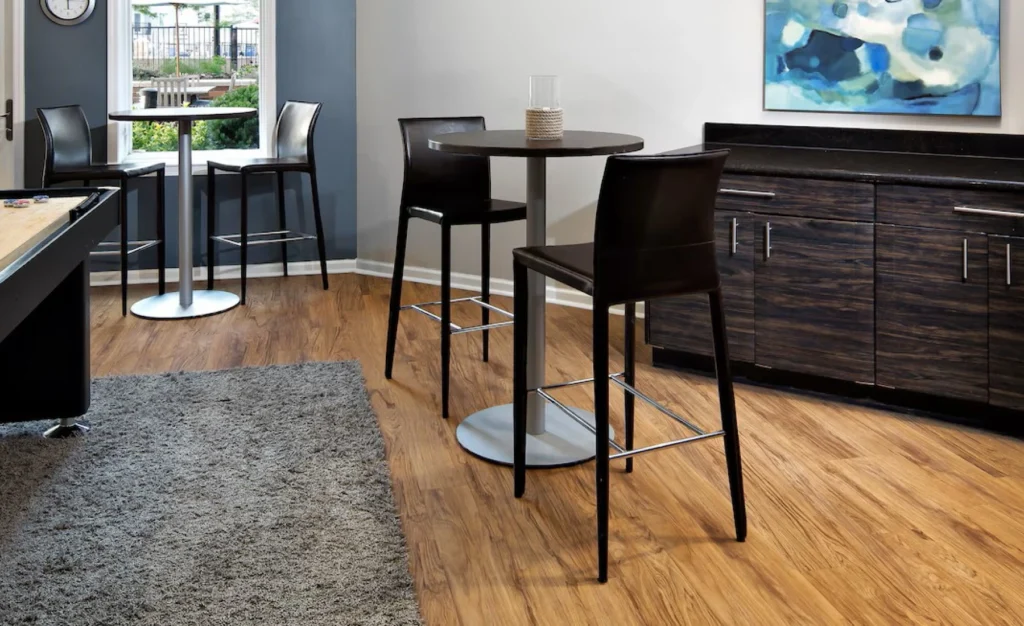 Modern apartment game lounge with high-top tables, dark cabinetry, and wood-style flooring