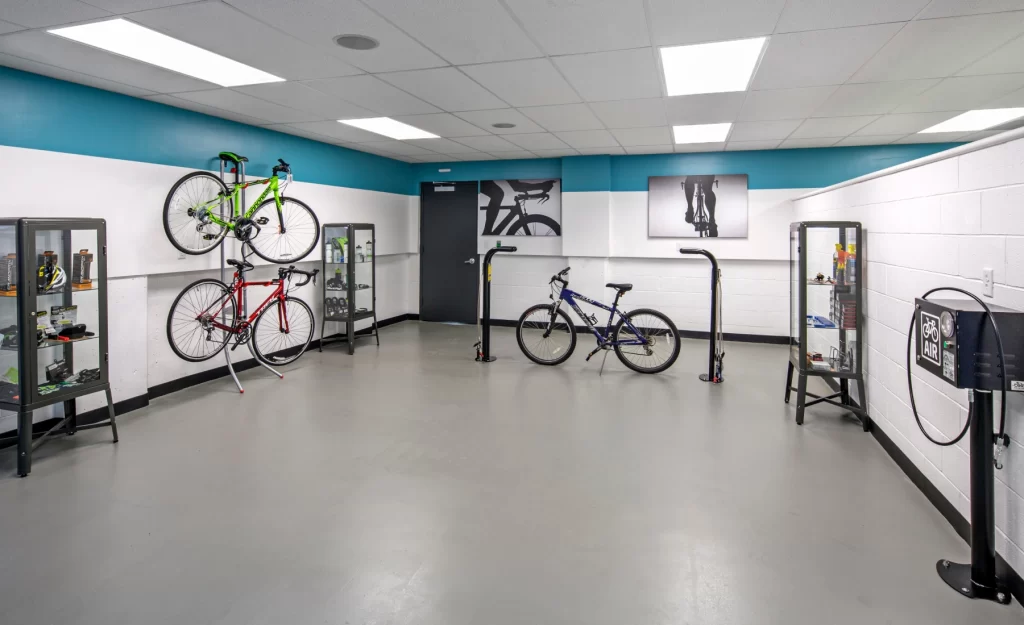Indoor bike repair station with hanging racks, tools, and displayed cycling gear in glass cases