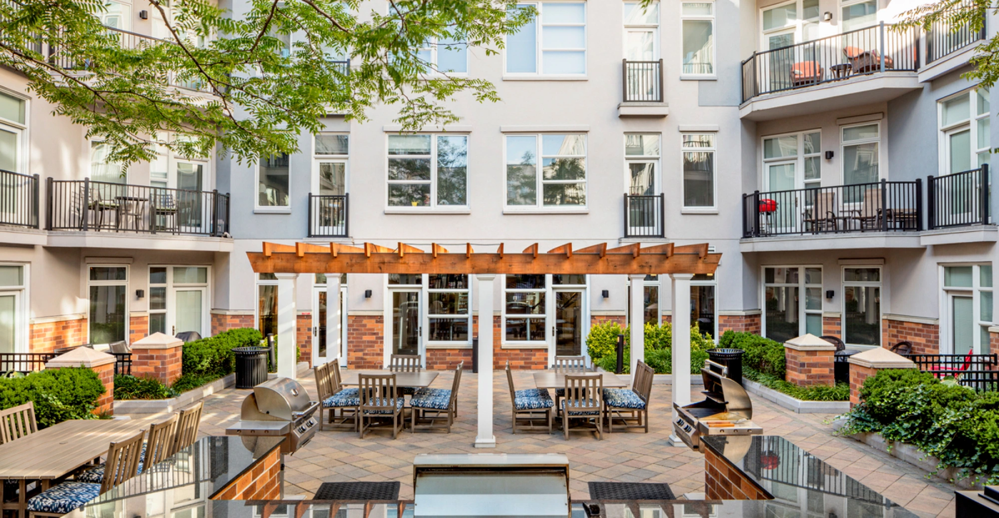 Modern Hoboken apartment complex courtyard featuring swimming pool, trees, and patio seating area