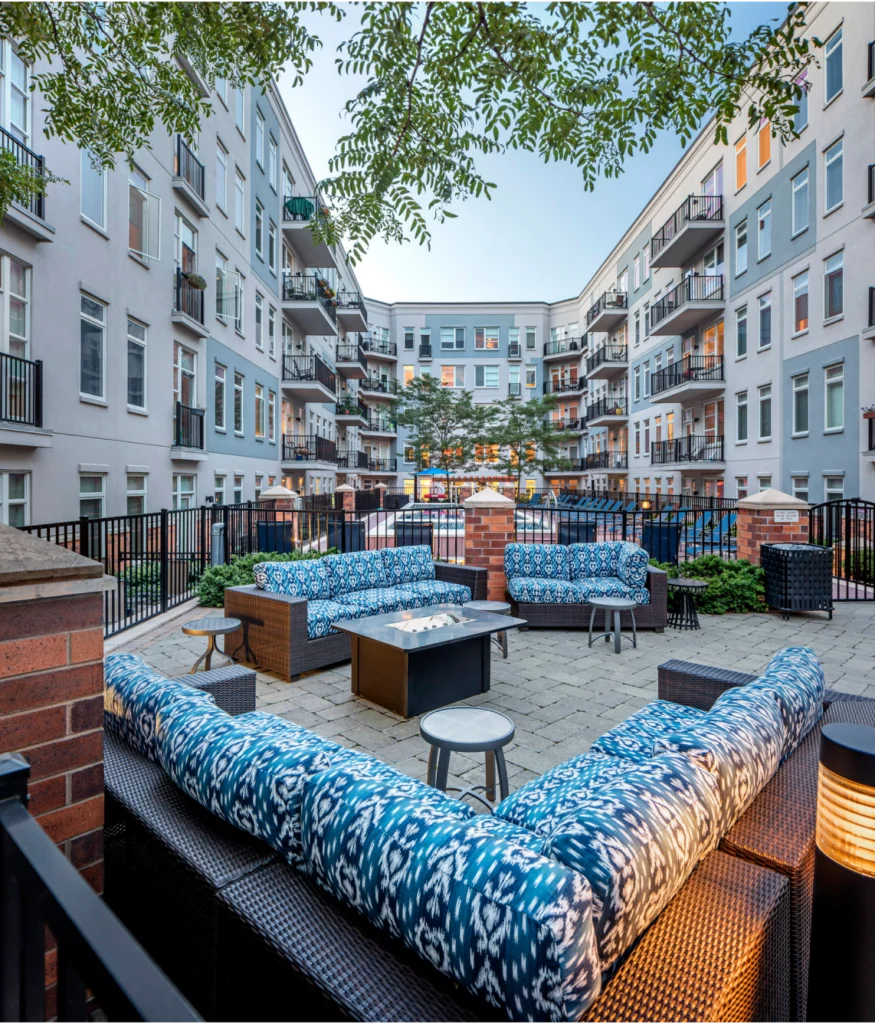 Outdoor courtyard with cushioned seating area and fire pit surrounded by luxury apartment balconies