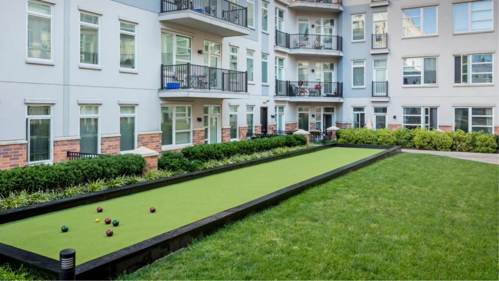 Residential bocce court on green lawn surrounded by shrubs and apartment balconies at Halstead Hoboken