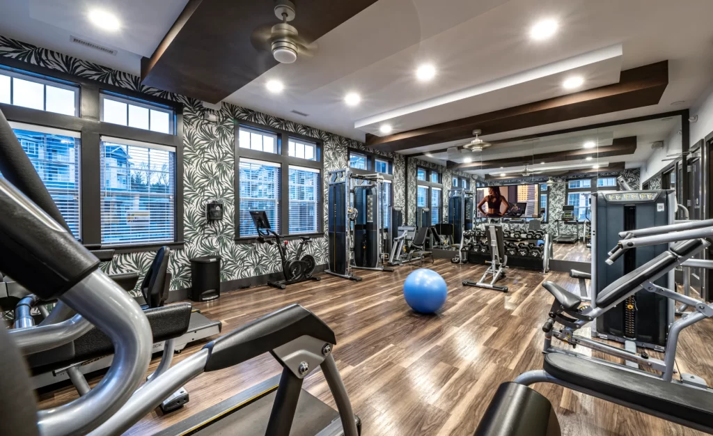 Fully equipped gym with strength machines, cardio equipment, and mirrors lining the wall