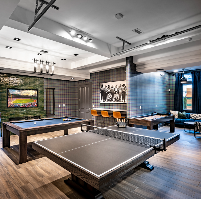 Game room with ping pong, pool tables, and lounge seating under decorative ceiling lights