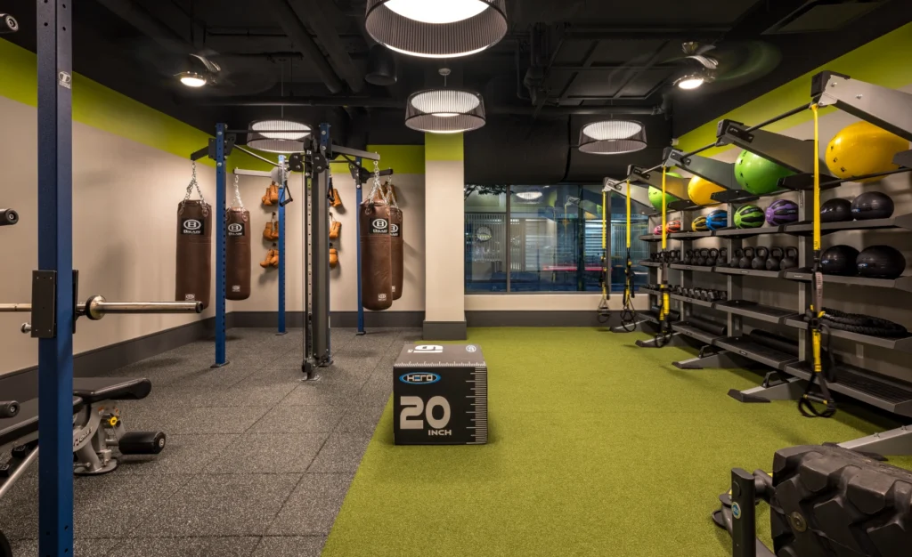 Functional gym area with punching bags, kettlebells, turf flooring, and weight training equipment