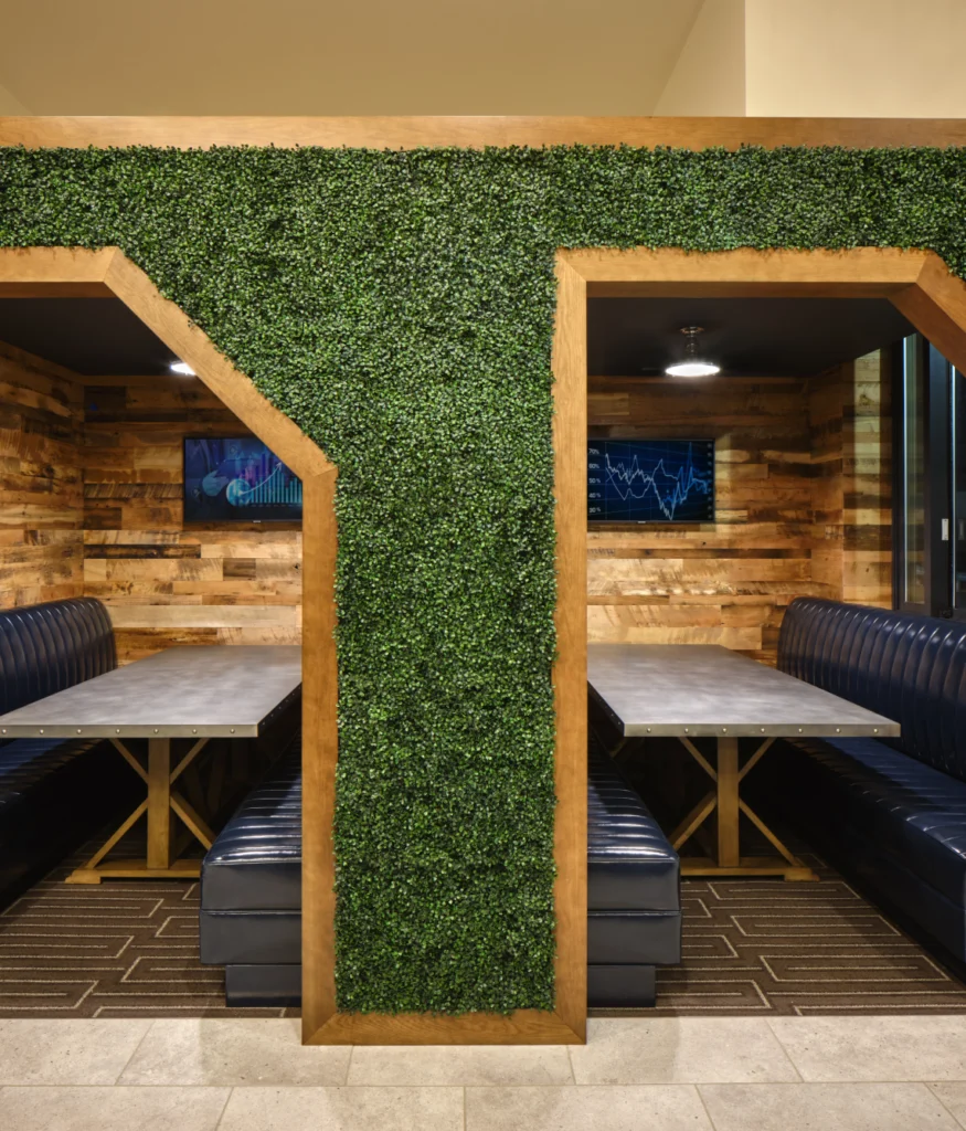 Cozy booth seating areas with wooden walls, industrial lighting, and artificial greenery divider