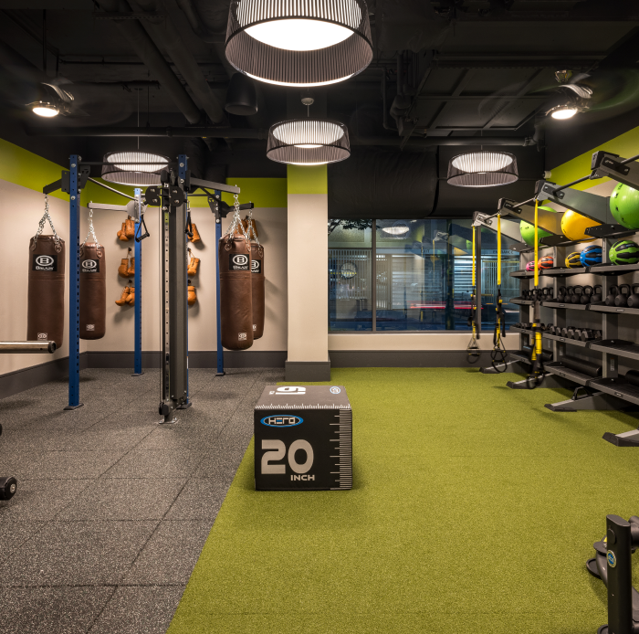 Functional gym area with punching bags, kettlebells, turf flooring, and weight training equipment